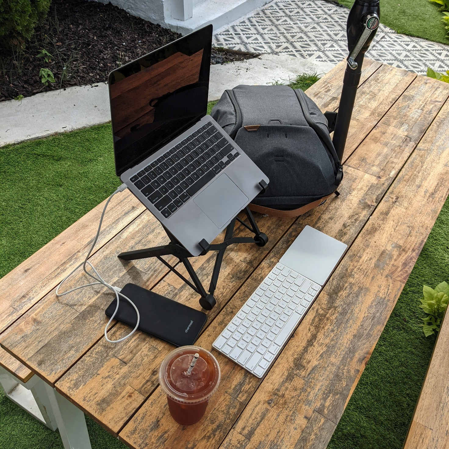 Casey's laptop setup outdoors: laptop on a stand, wireless trackpad and keyboard, headset, iced tea - all on a picnic table